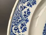 a close up of a blue and white plate with a bird on it