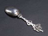 a silver spoon with a bird on it on a black surface
