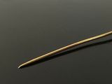 a close up of a gold plated hair pin on a black surface