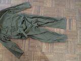 a green jacket laying on the floor next to a pair of shoes