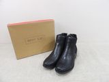 a pair of black boots sitting next to a cardboard box