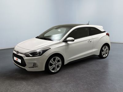 La voiture blanche est garée dans une pièce au sol gris.