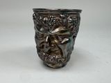 a silver vase with a face on it