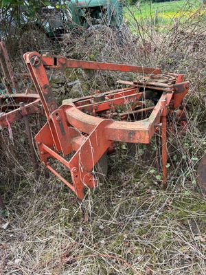 un vieux tracteur rouillé et une charrue au milieu des mauvaises herbes