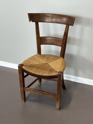une chaise en bois avec une assise en osier, dans un coin de la pièce