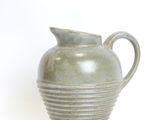 a green vase that is sitting on a white surface