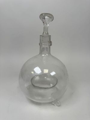 une carafe en verre transparent munie d'un bouchon en métal, sur fond blanc