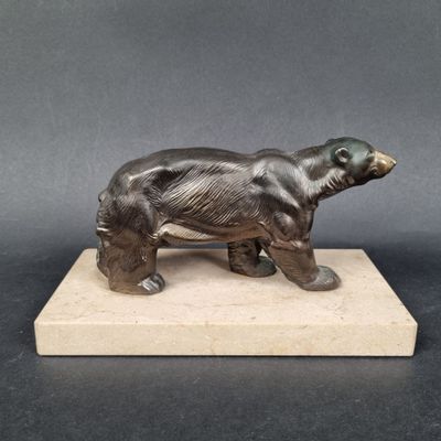 sculpture en bronze représentant un ours, posée sur un socle en marbre, sur un fond gris