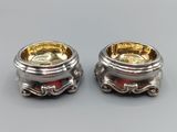 pair of silver and gold plated candlestick holders on a grey surface