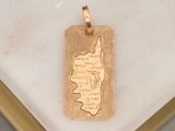 a gold pendant with a map on it on a marble table