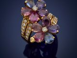 a close up of a gold ring with pink and blue sapphires