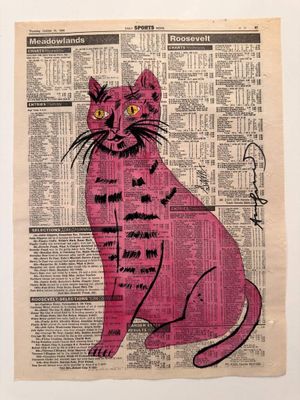 a pink cat sitting on top of a newspaper