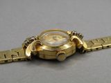 a gold watch that is sitting on a silver surface