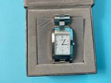 a silver and blue watch in a box on a blue surface