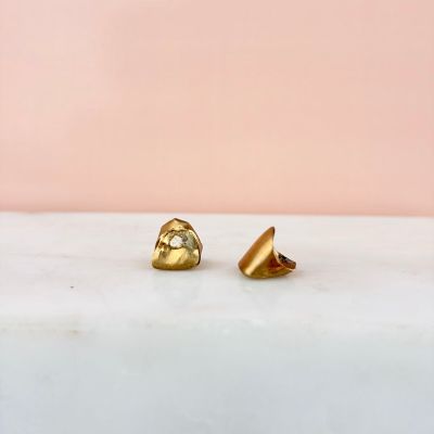 a pair of gold earrings sitting on top of a marble counter