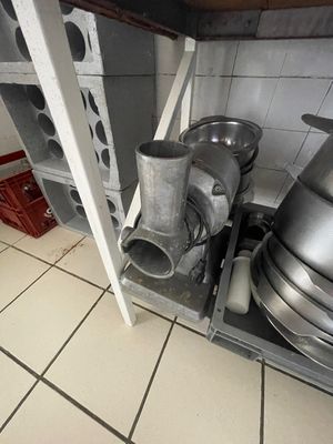 Des casseroles et des poêles sont empilées sur une étagère en métal dans une cuisine.