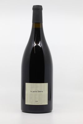the bottle of wine is sitting on a white surface