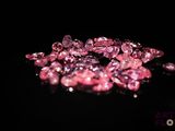 some pink diamonds on a black surface with a black background