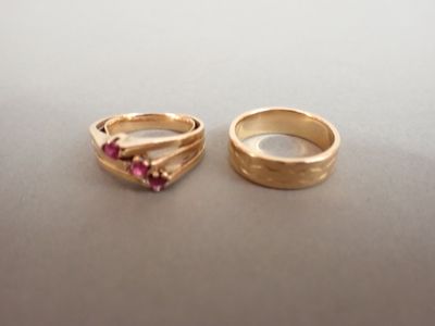 une paire d'alliances en or ornées de pierres roses, posées sur une table