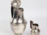 a silver pitcher and a silver cup on a white background