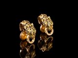 pair of gold leopard earrings on black background with reflection