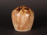 a brown and white vase sitting on a black surface