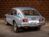 a silver car parked in front of a brick wall