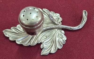 une salière et une poivrière en argent posées sur un napperon rouge