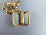 a picture of a gold and green broochle with a bow
