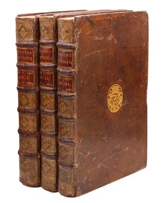 un ensemble de livres anciens composé de trois volumes reliés en cuir marron empilés les uns sur les autres