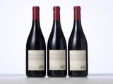 three bottles of red wine sitting on top of a table