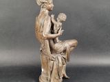 statue of a woman sitting on a stool holding a flower