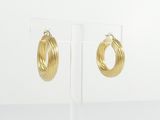 a pair of gold hoop earrings on a clear stand