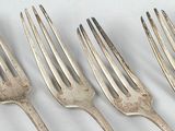 five forks that are lined up on a white surface