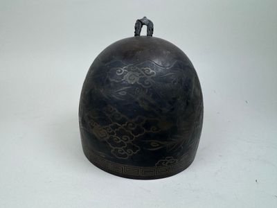 a black bell that is sitting on a white surface