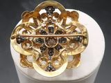 an image of a gold broochle with black stones on it