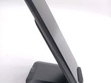 a black cell phone on a stand on a white surface