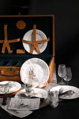 une valise sur laquelle est posé un service d'assiettes et de verres
