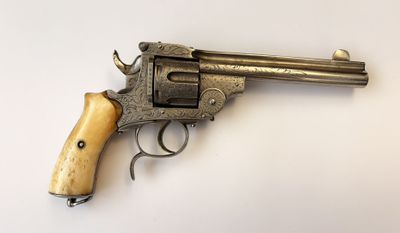 un vieux revolver avec une poignée en bois sur une surface blanche