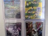 four pokemon cards in plastic cases on a white surface