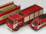 quatre camions de pompiers miniatures et un vrai camion de pompiers posés sur une table
