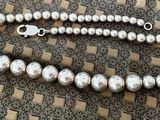 a silver bead necklace with a silver clasp on a table