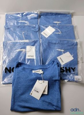 four blue t - shirts in plastic bags on a table
