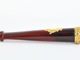 an image of a red and gold pipe sitting on top of a white surface