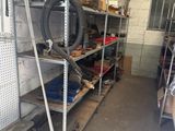 un homme debout dans un garage, à côté d'une étagère remplie d'outils