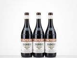 three bottles of red wine sit on a white surface