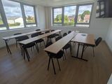 des tables et des chaises dans une pièce où est accrochée une télévision à écran plat au mur