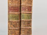 two old books sitting on top of each other on a white surface