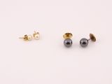 une paire de boucles d'oreilles à clous en or et perles noires