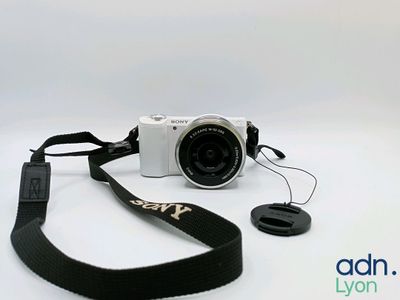 a white camera with a black strap on a white background